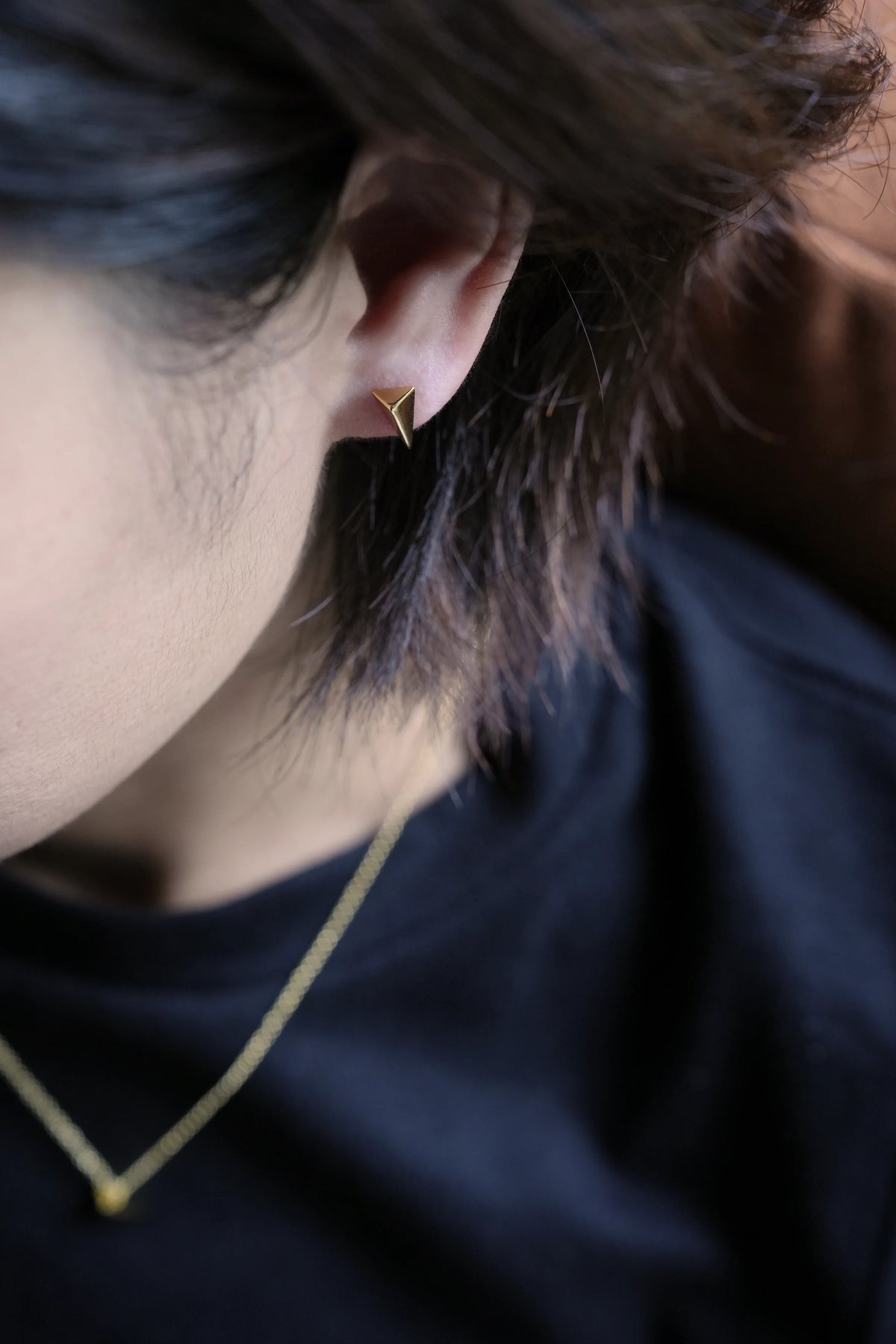 Model wearing a ShingoWorks gold-tone pendant necklace with a small triangle pendant and matching stud earring